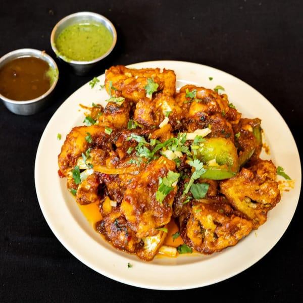 Spicy paneer chili with green peppers and cilantro, served with two dipping sauces.
