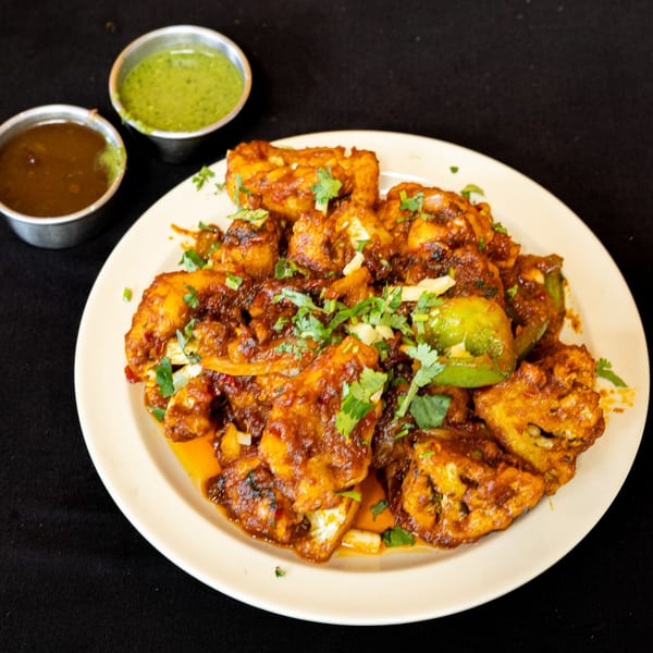 Spicy Indian paneer chili with bell peppers and cilantro, served with two dipping sauces.
